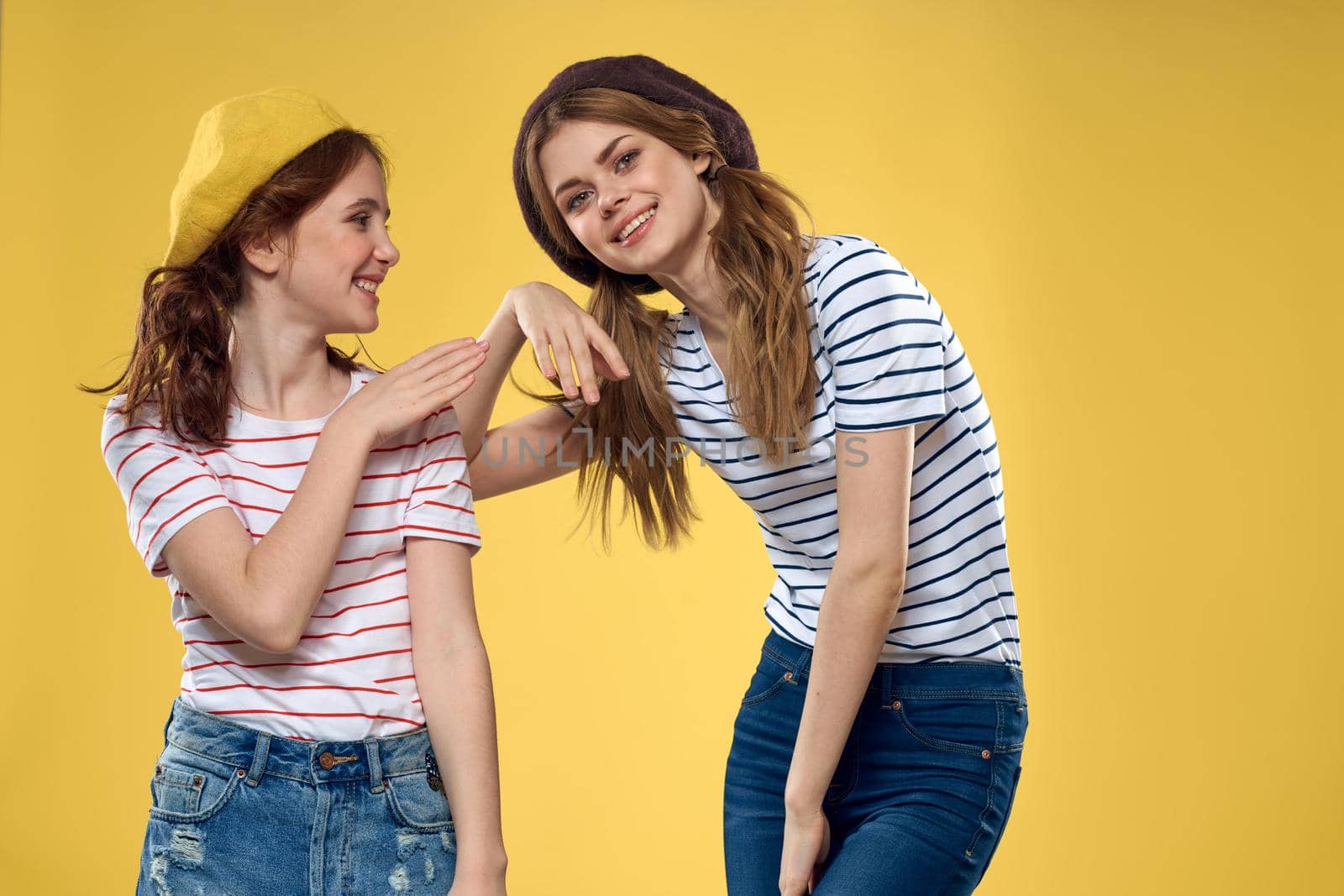 funny mom and daughter wearing hats fashion fun joy family yellow background. High quality photo