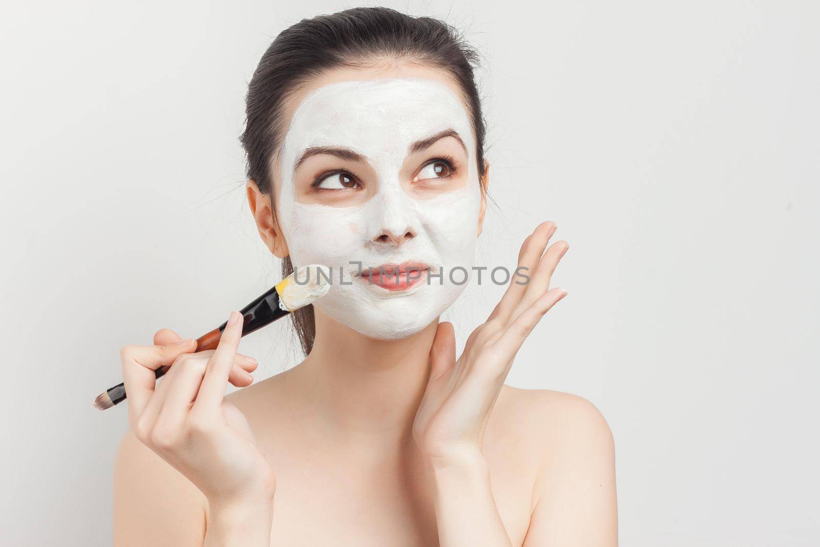 woman with bare shoulders apply brush face mask skin care spa treatments. High quality photo