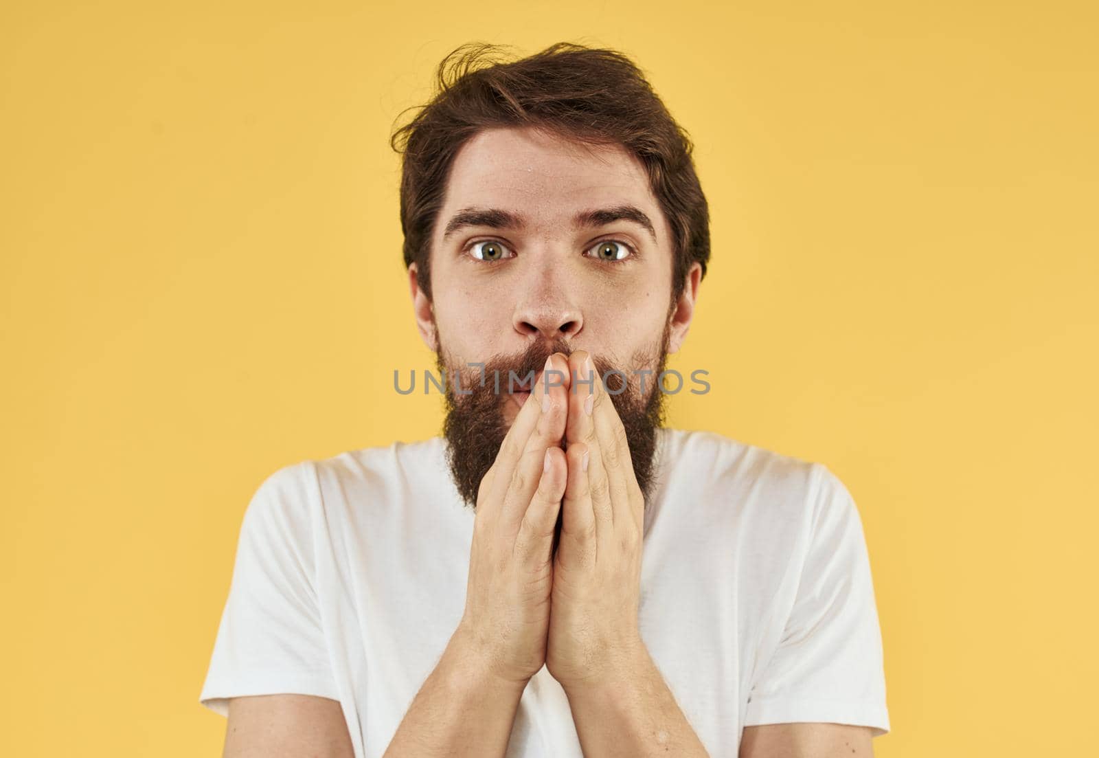 Upset man holds his hands near his face on a yellow background by SHOTPRIME