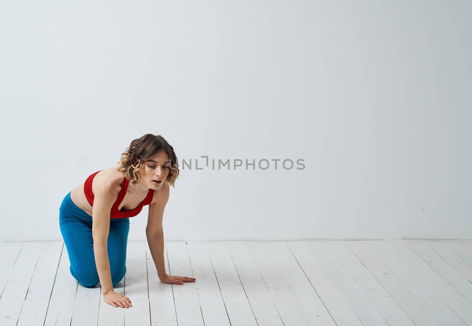 A slender woman is engaged in yoga for beginners on a light background in full growth by SHOTPRIME
