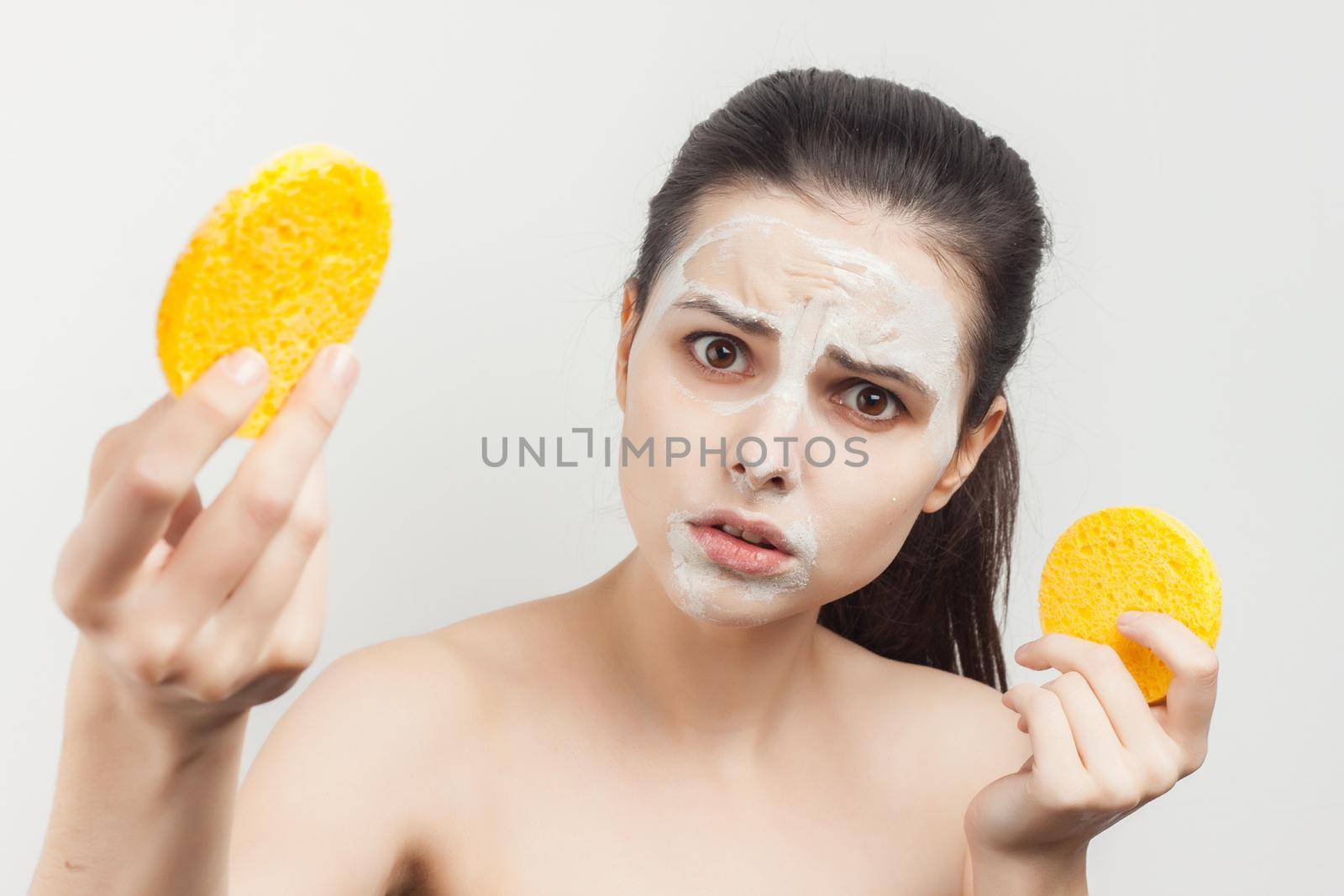 Cheerful brunette wipes her mask with a sponge scrub skincare. High quality photo