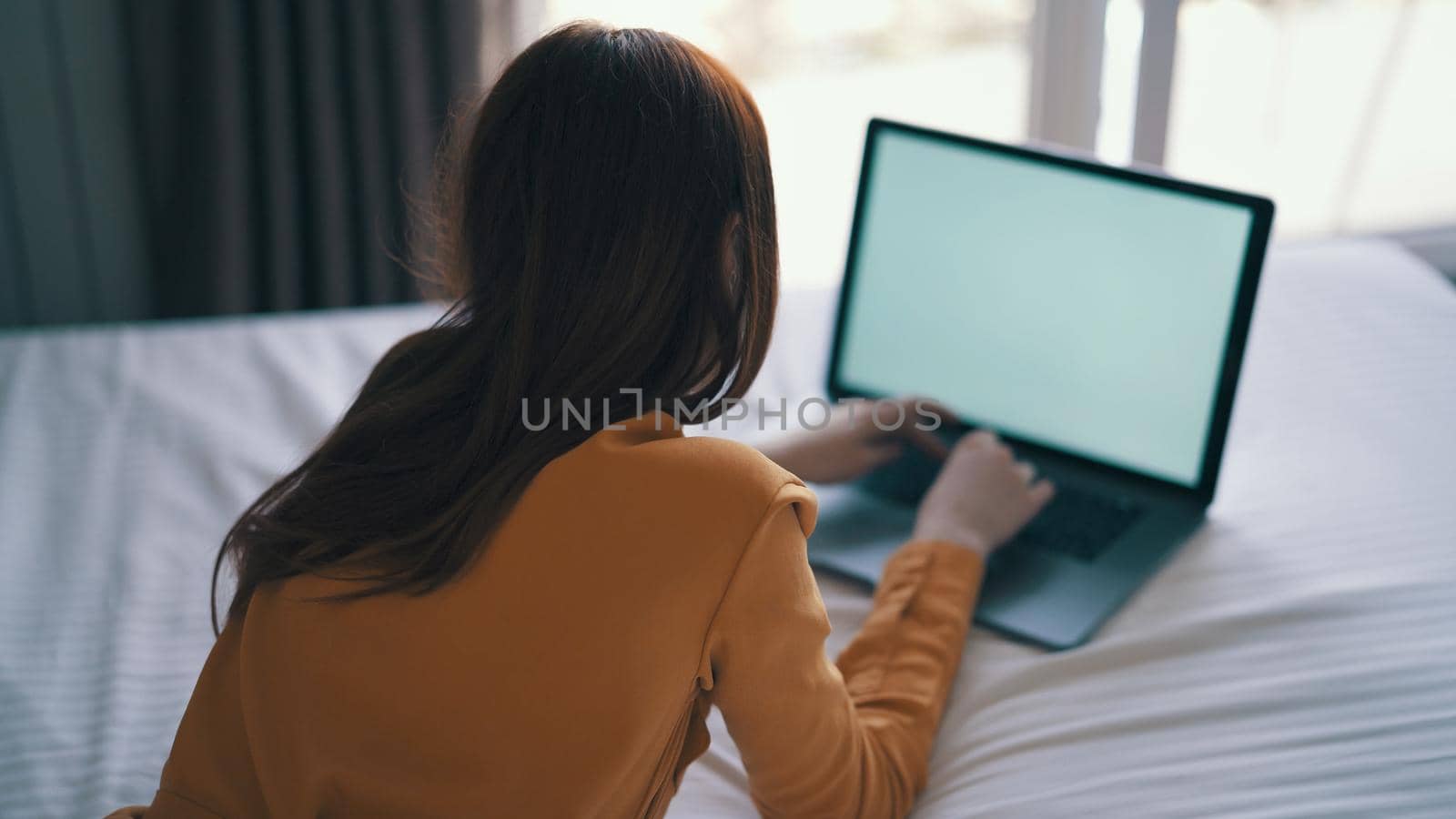 woman lying on bed working in front of laptop at home internet by SHOTPRIME