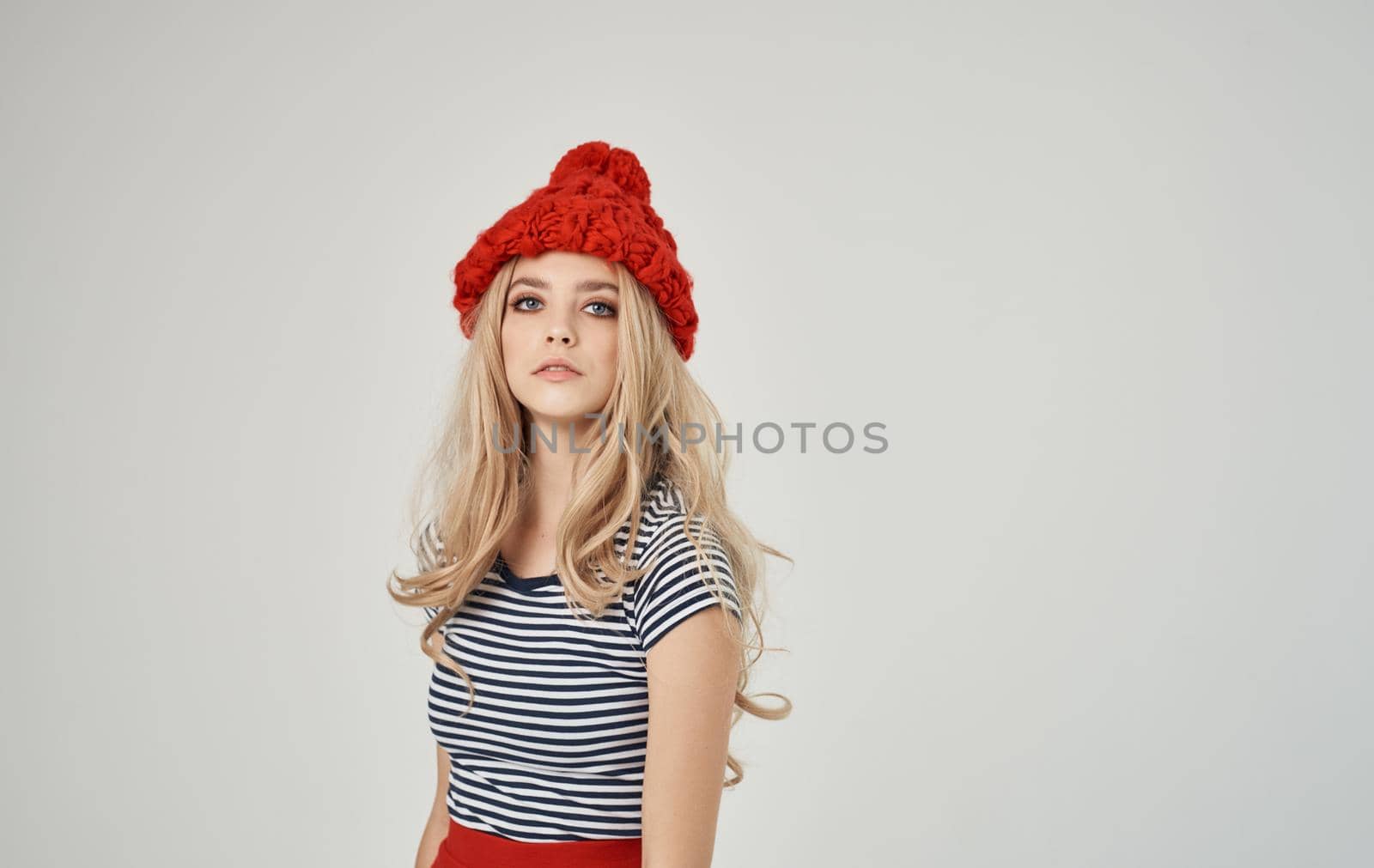 blonde woman in striped t-shirt and red hat portrait on light background cropped view. High quality photo