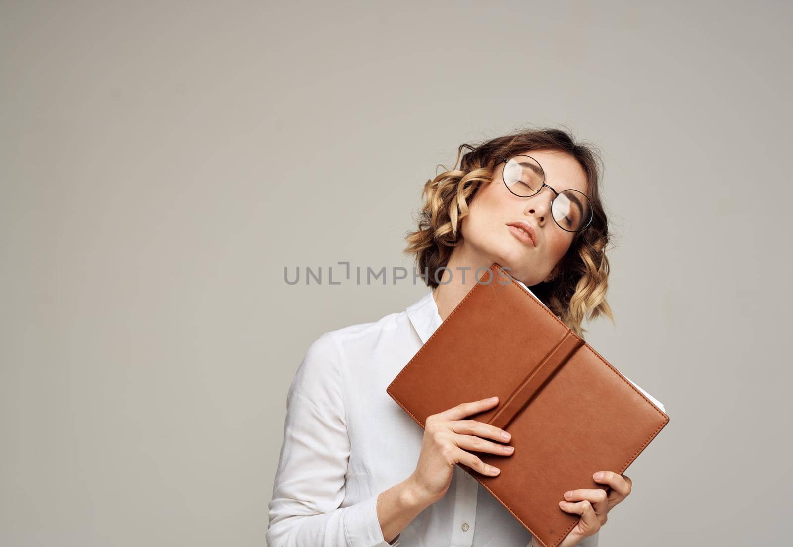Business woman with open notebook in her hands and glasses on her face, white shirt by SHOTPRIME