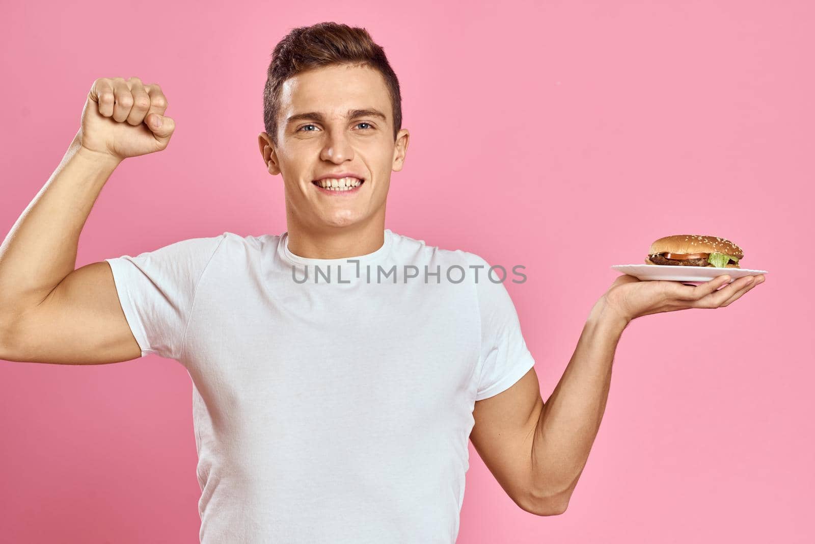 man in white t-shirt hamburger lifestyle pink background eating. High quality photo