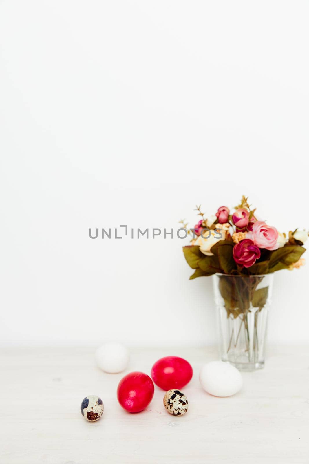 bouquet of fragrant flowers and Easter eggs on a wooden table In a bright room by SHOTPRIME