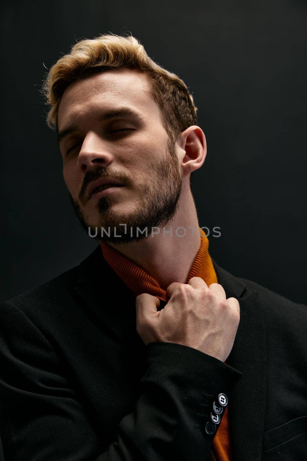 blond man touches his neck and orange sweater jacket trend of the season . High quality photo