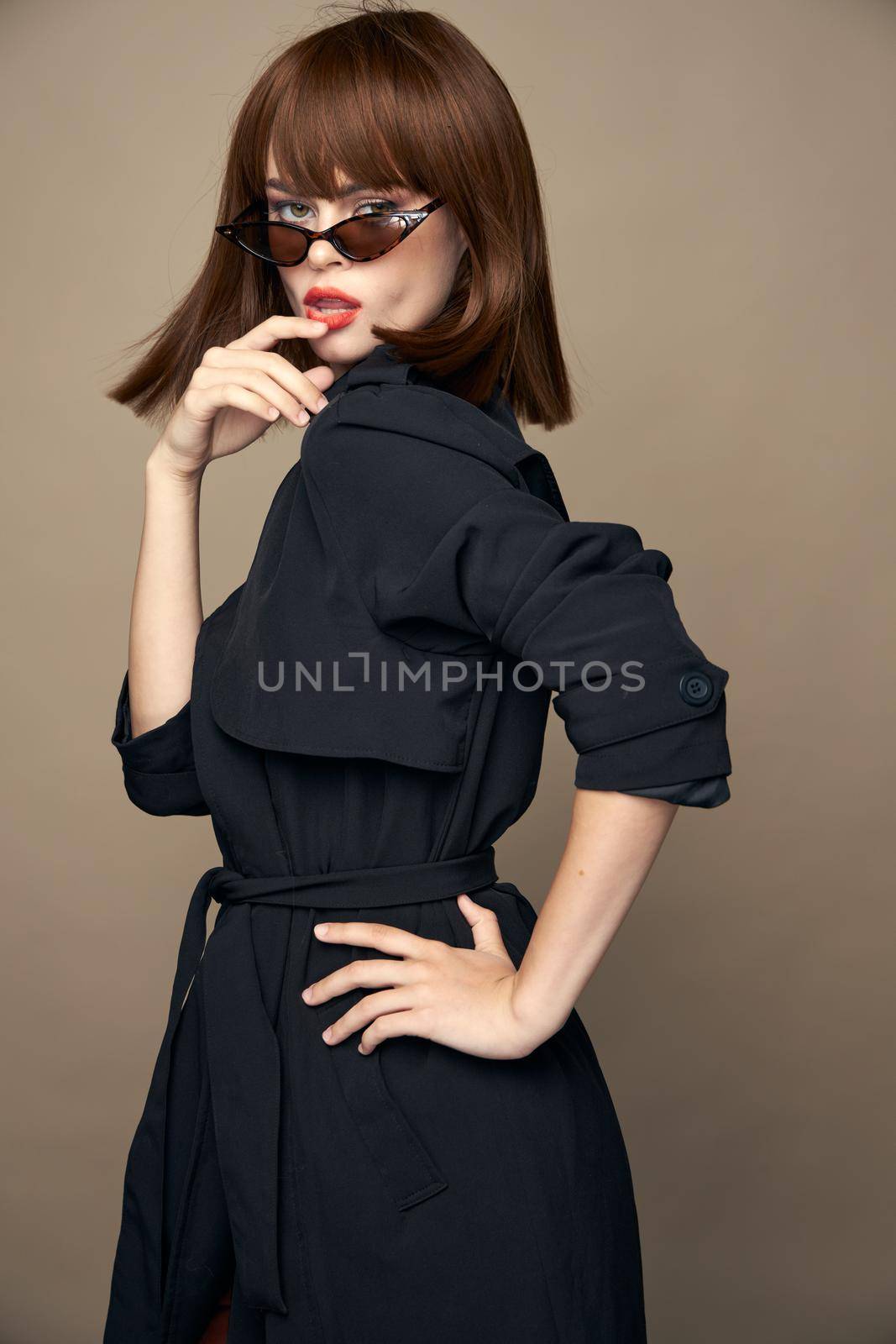 Fashionable woman Black coat and passionate look dark glasses studio