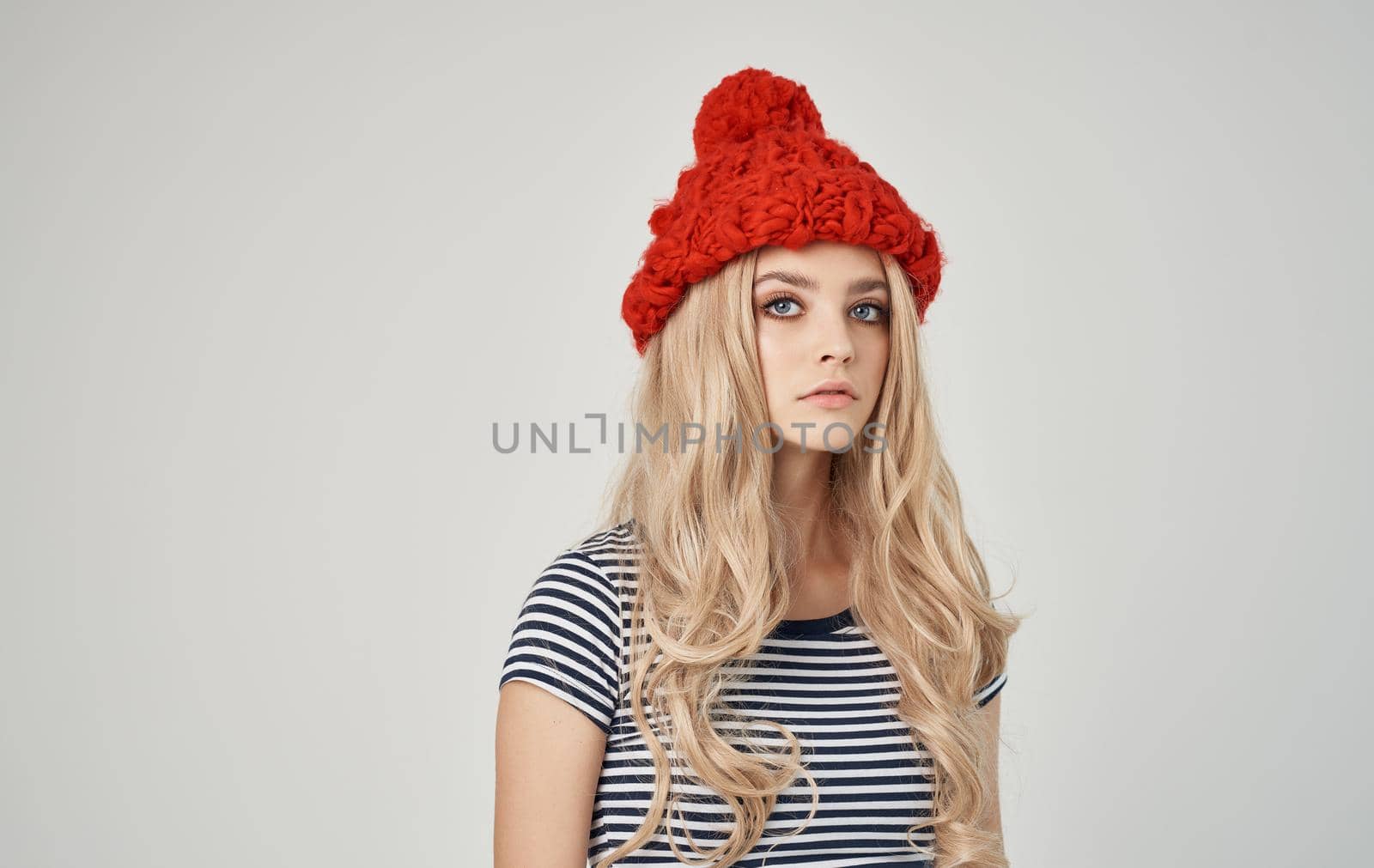 emotional blonde woman in striped t-shirt with cap on her head on phone cropped view. High quality photo