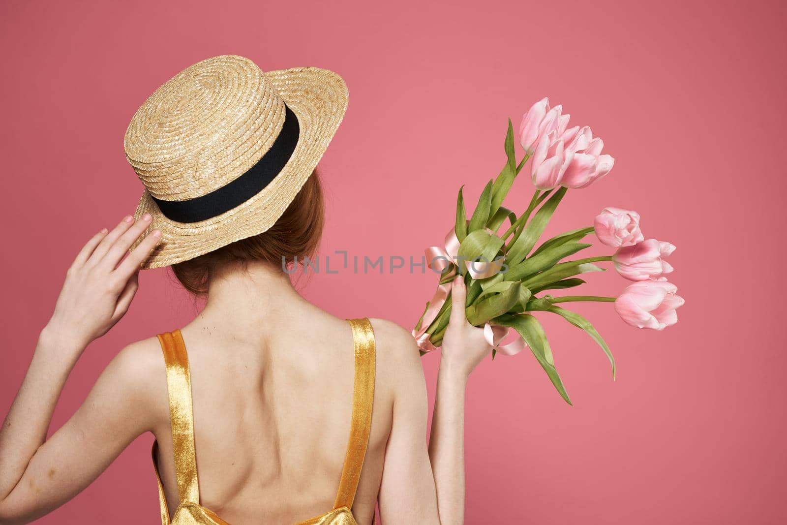 woman with hat back view bouquet of flowers as a gift pink background by SHOTPRIME