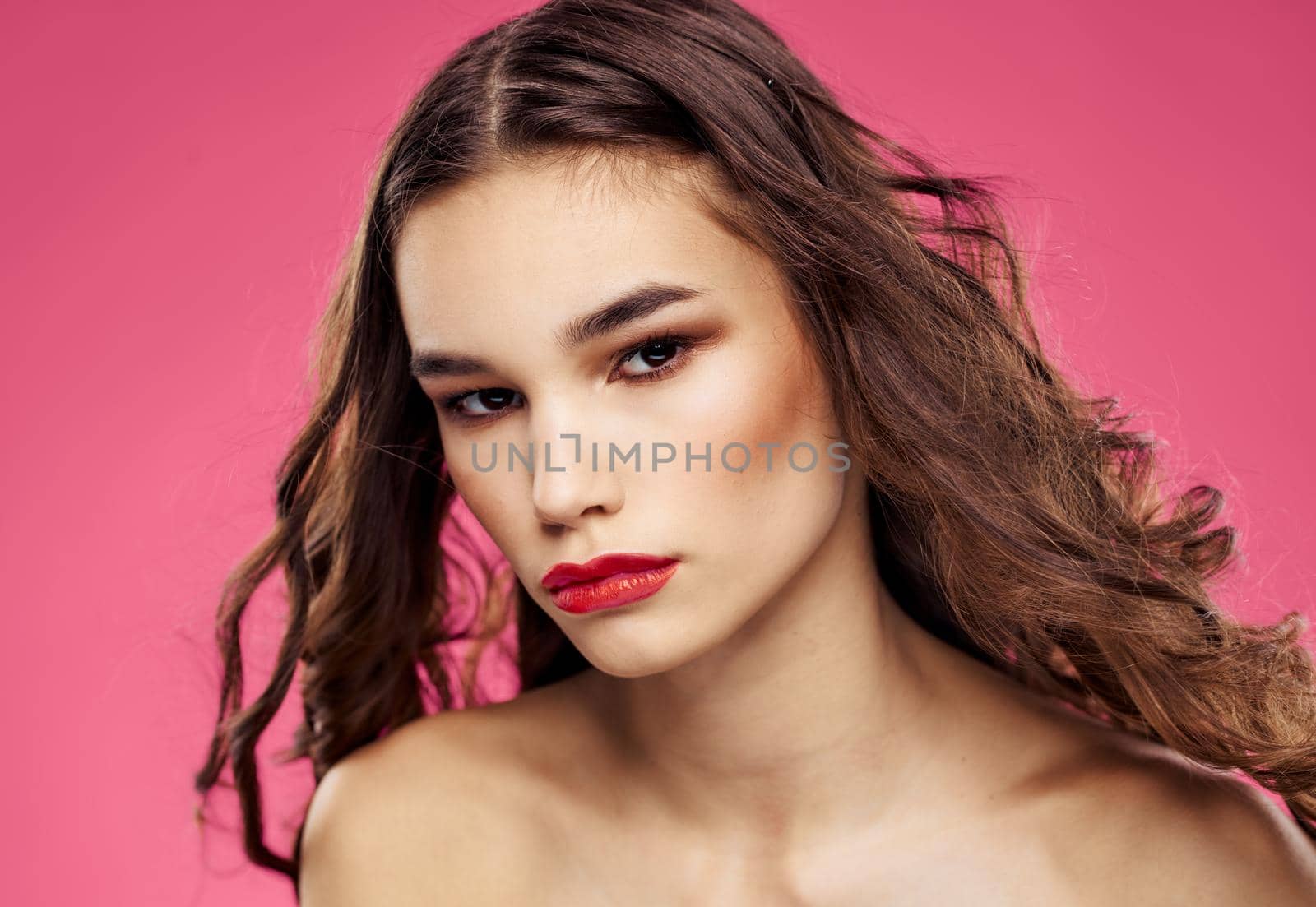 Pink background female portrait bared shoulders red lips. High quality photo