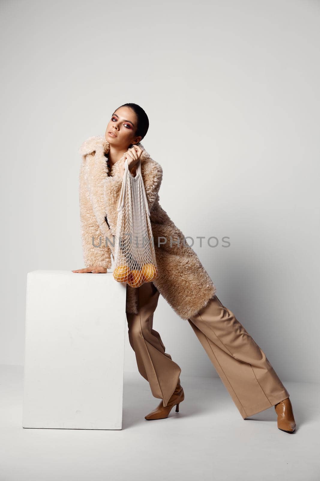 pretty woman with bright makeup beige coat mesh with oranges Studio. High quality photo