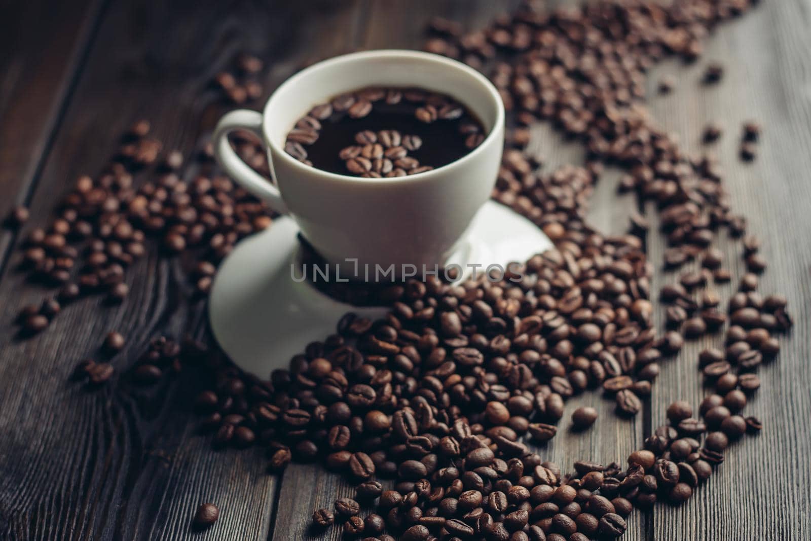 a cup of hot coffee on a wooden table and sprinkled beans close-up by SHOTPRIME