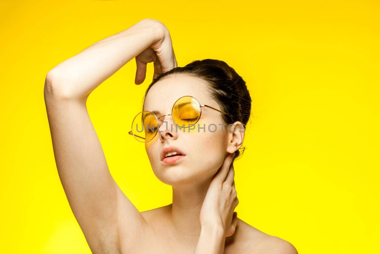 woman with bare shoulders clear skin yellow glasses hand gesture. High quality photo