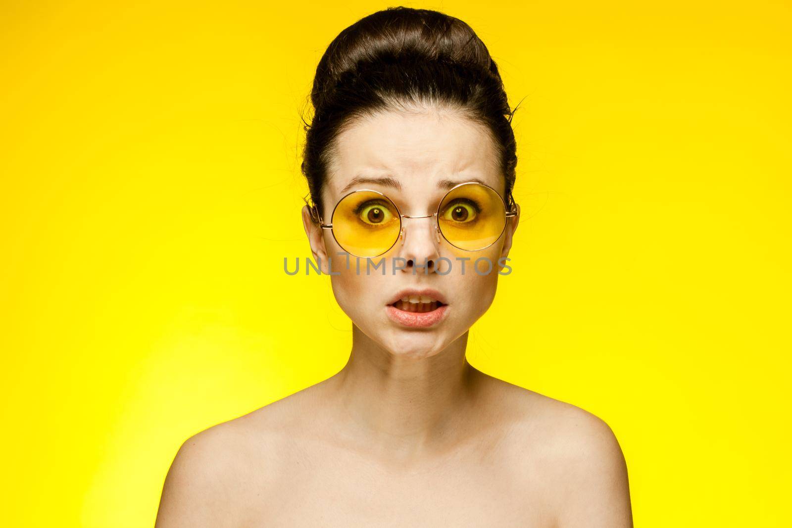 attractive woman with bare shoulders yellow glasses isolated background. High quality photo