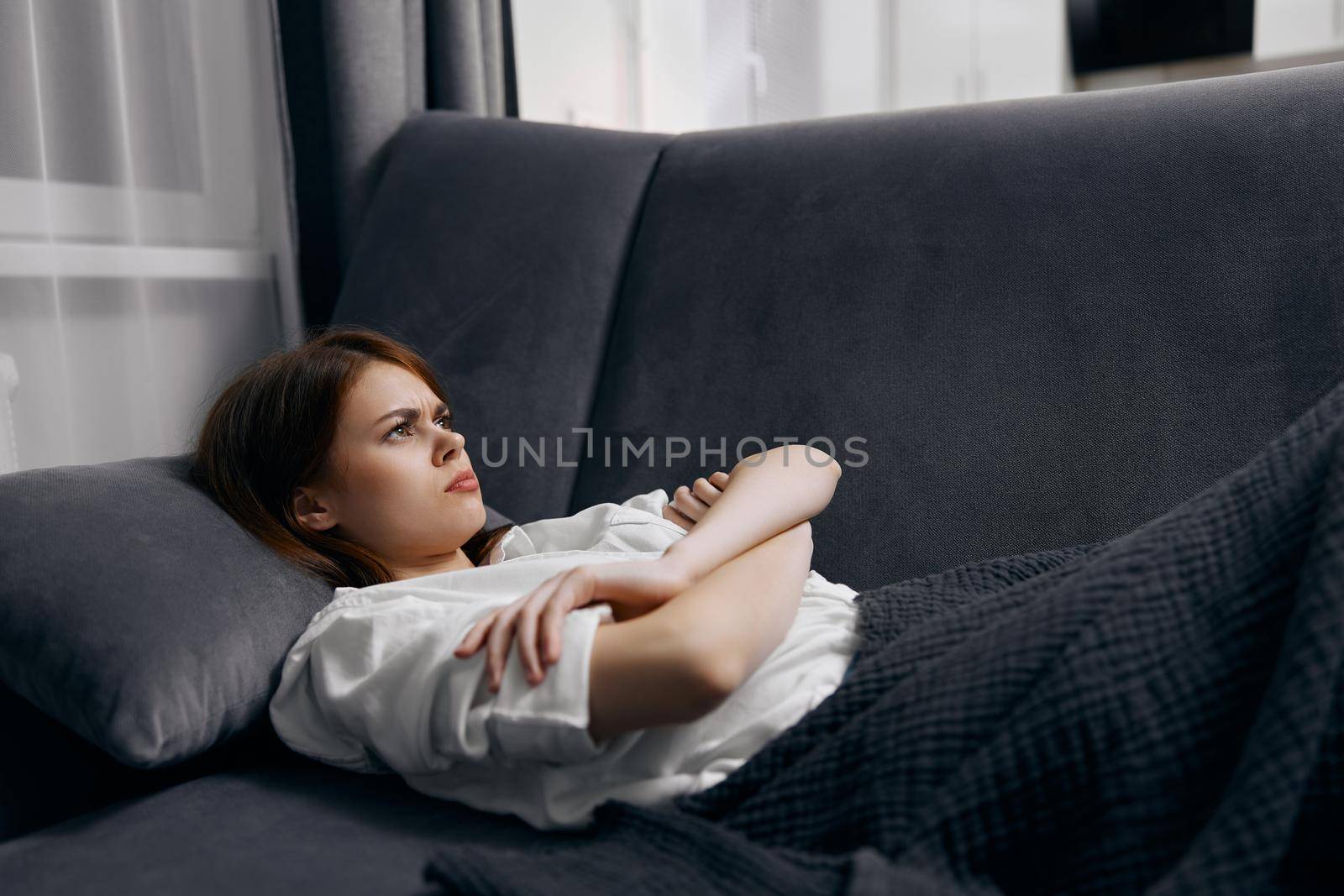 offended woman lies on the sofa in the room under a warm blanket close-up by SHOTPRIME