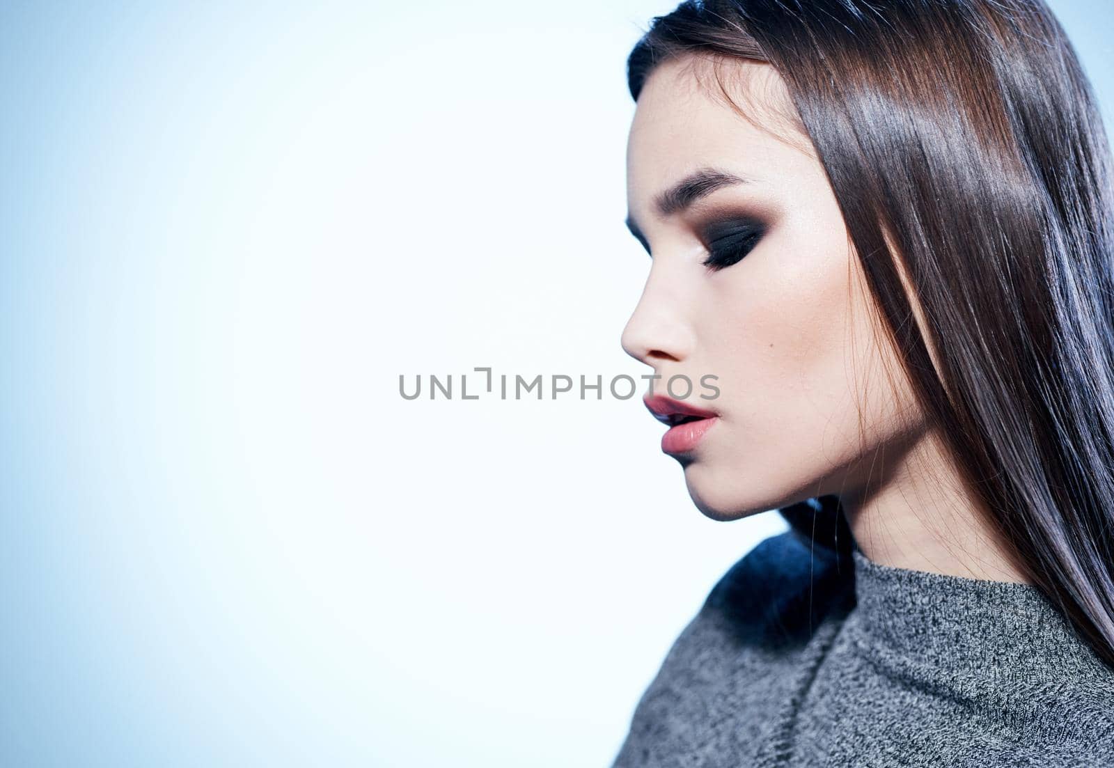 Portrait of a beautiful brunette in a gray sweater and eye shadow, evening makeup. High quality photo