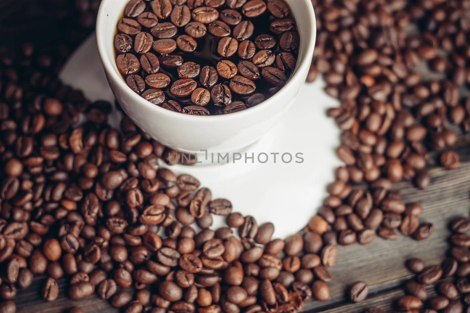 coffee beans on a wooden background and a cup on a saucer close-up macro photography. High quality photo