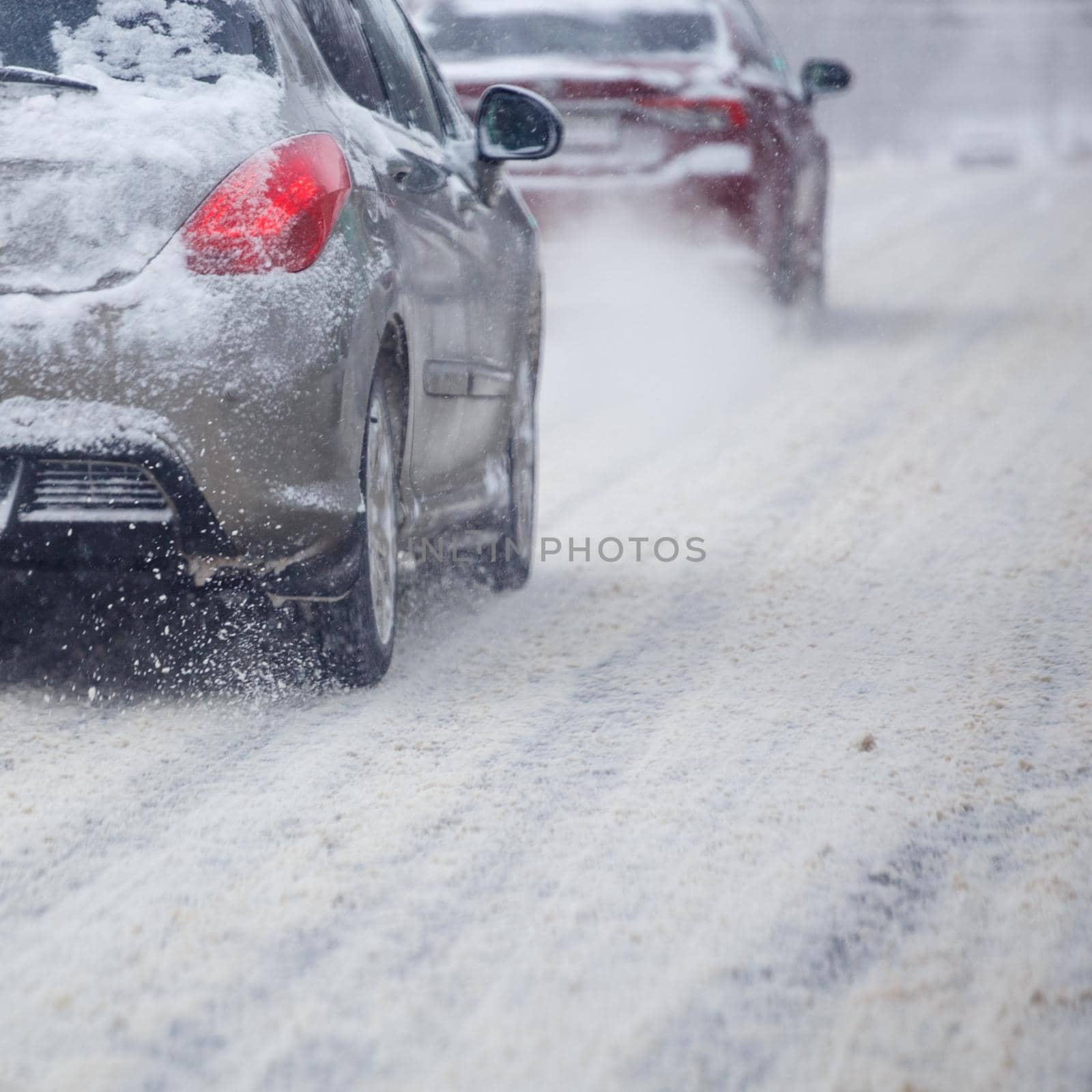 Road snow pieces flow from wheels of dirty car moving fast in daylight city with selective focus. by z1b