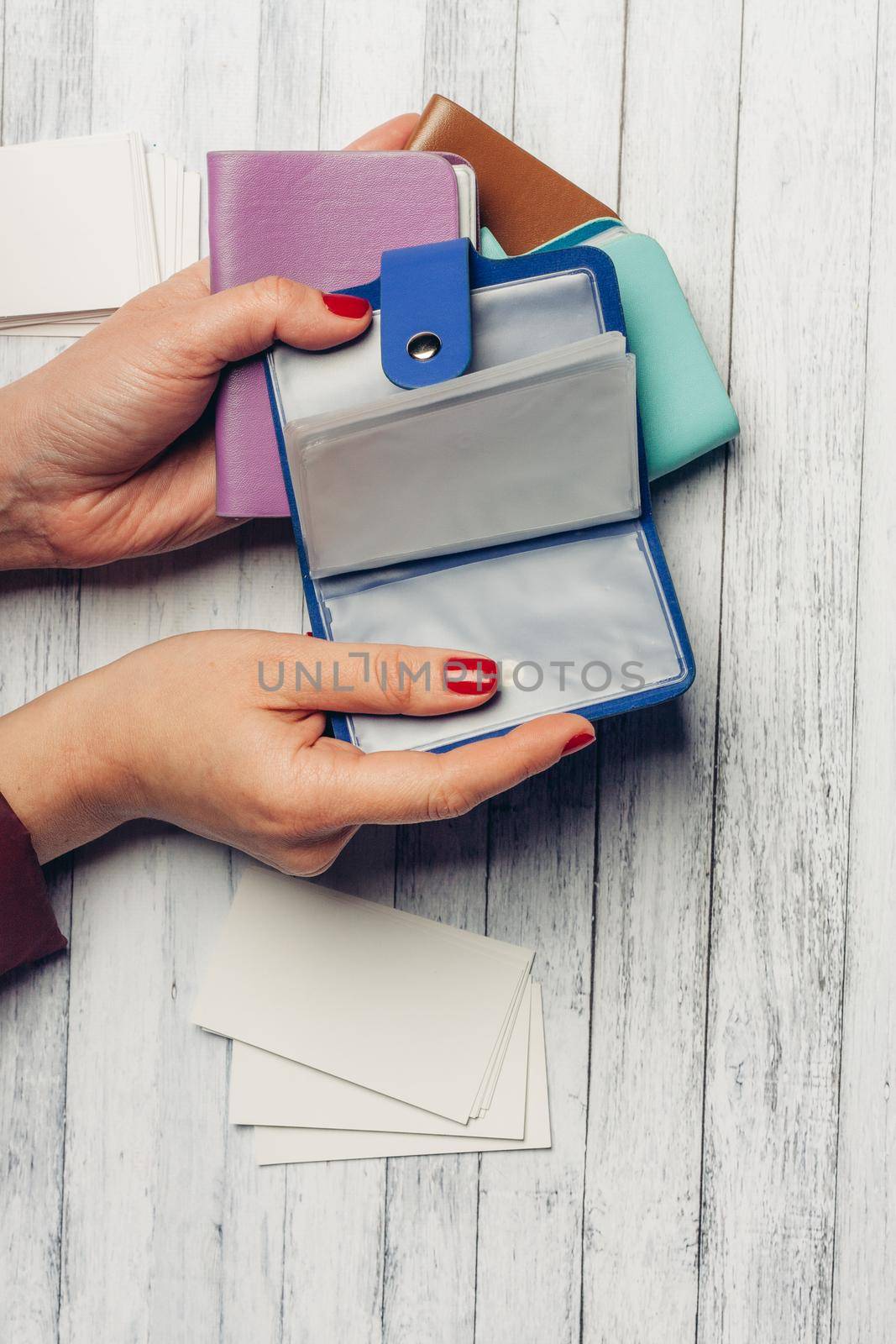 business card holder in female hands on a wooden background top view texture. High quality photo