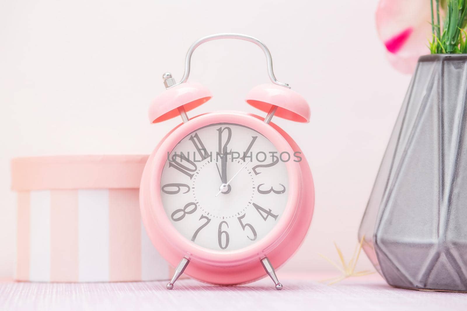 Gentle pink alarm clock next to a vase of flowers and a decorative gift box by galinasharapova