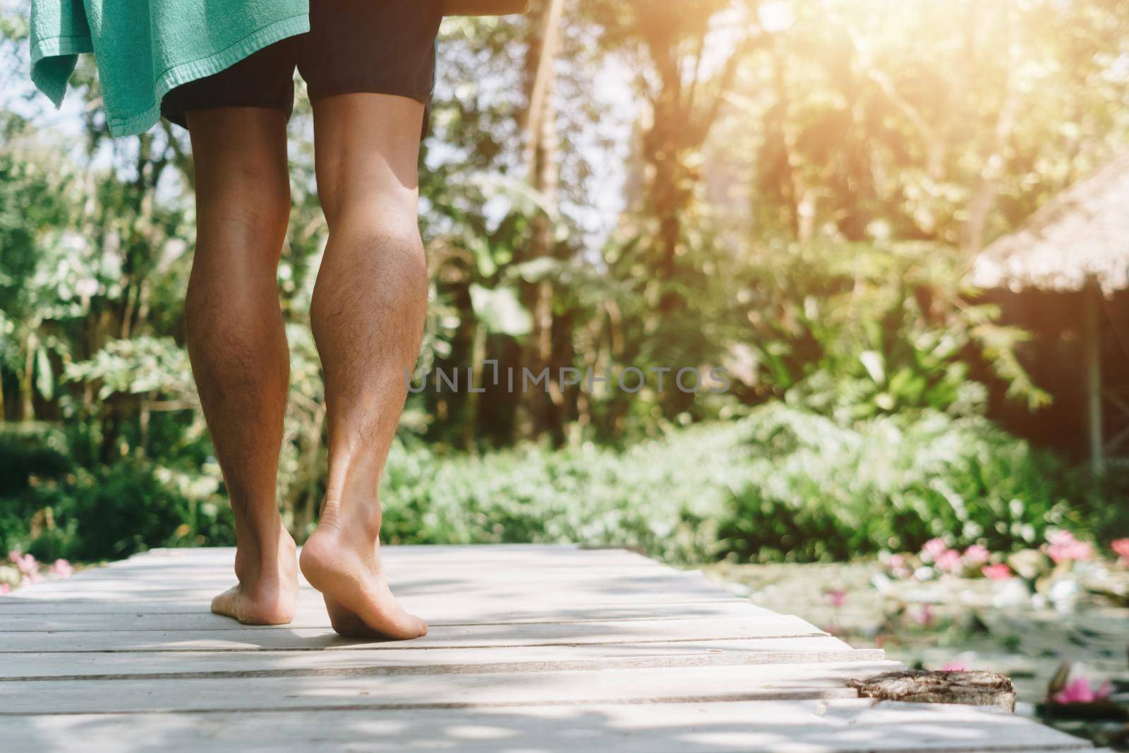 Woman is walking on small wood bridge to nature walk way with sunlight flare background.