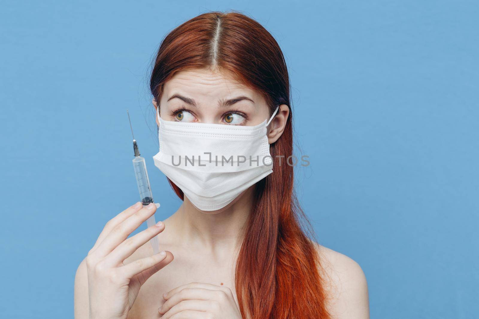 woman in medical mask holds syringe in hand and bare shoulders botox injection. High quality photo