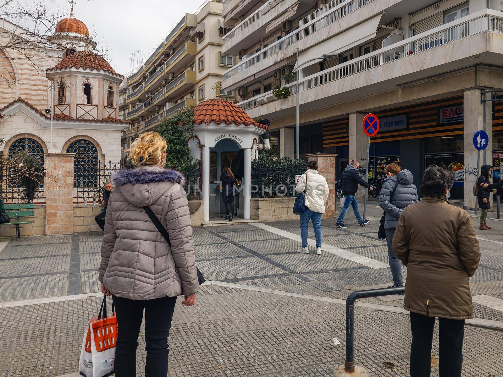 Greeks with coronavirus masks wait to practice their religious worship outside an Orthodox church.