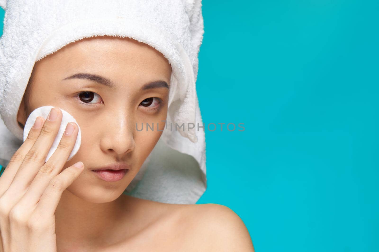 pretty woman towel on head wiping face with cotton pad health blue background. High quality photo