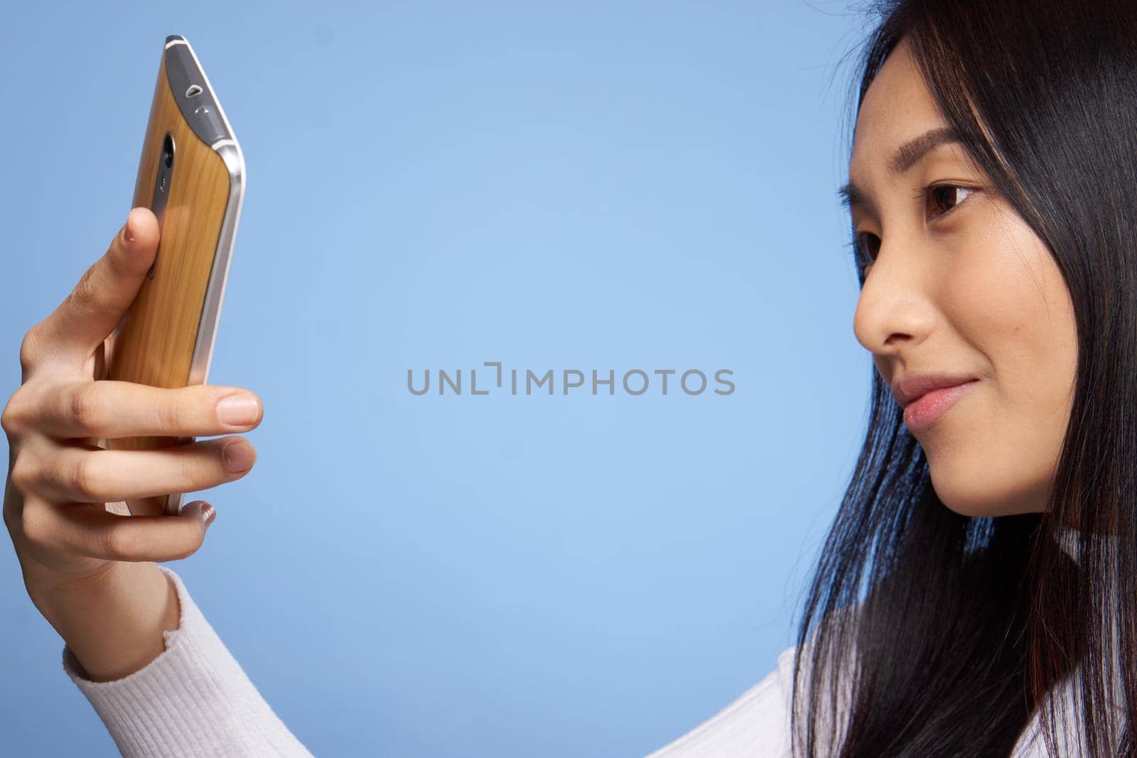 pretty brunette with phone in hands communication internet technology blue background studio by SHOTPRIME