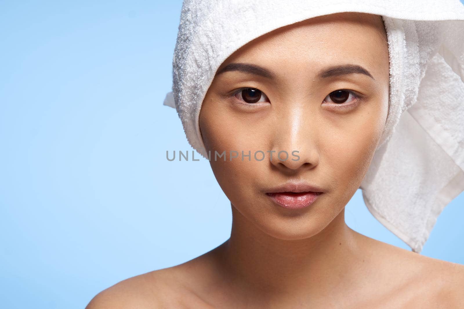 pretty asian woman clean skin care towel on head blue background. High quality photo