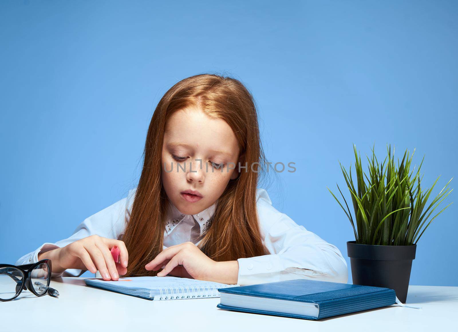 red-haired girl sitting at a table with textbooks lessons school training. High quality photo