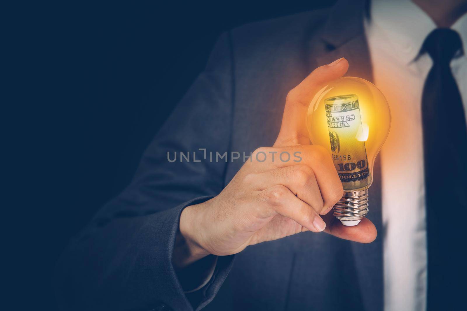 Hand of businessman holding light bulb having currency dollar, success of finance, innovation and energy, planning with financial saving, vision and knowledge, lightbulb glowing, business concept.