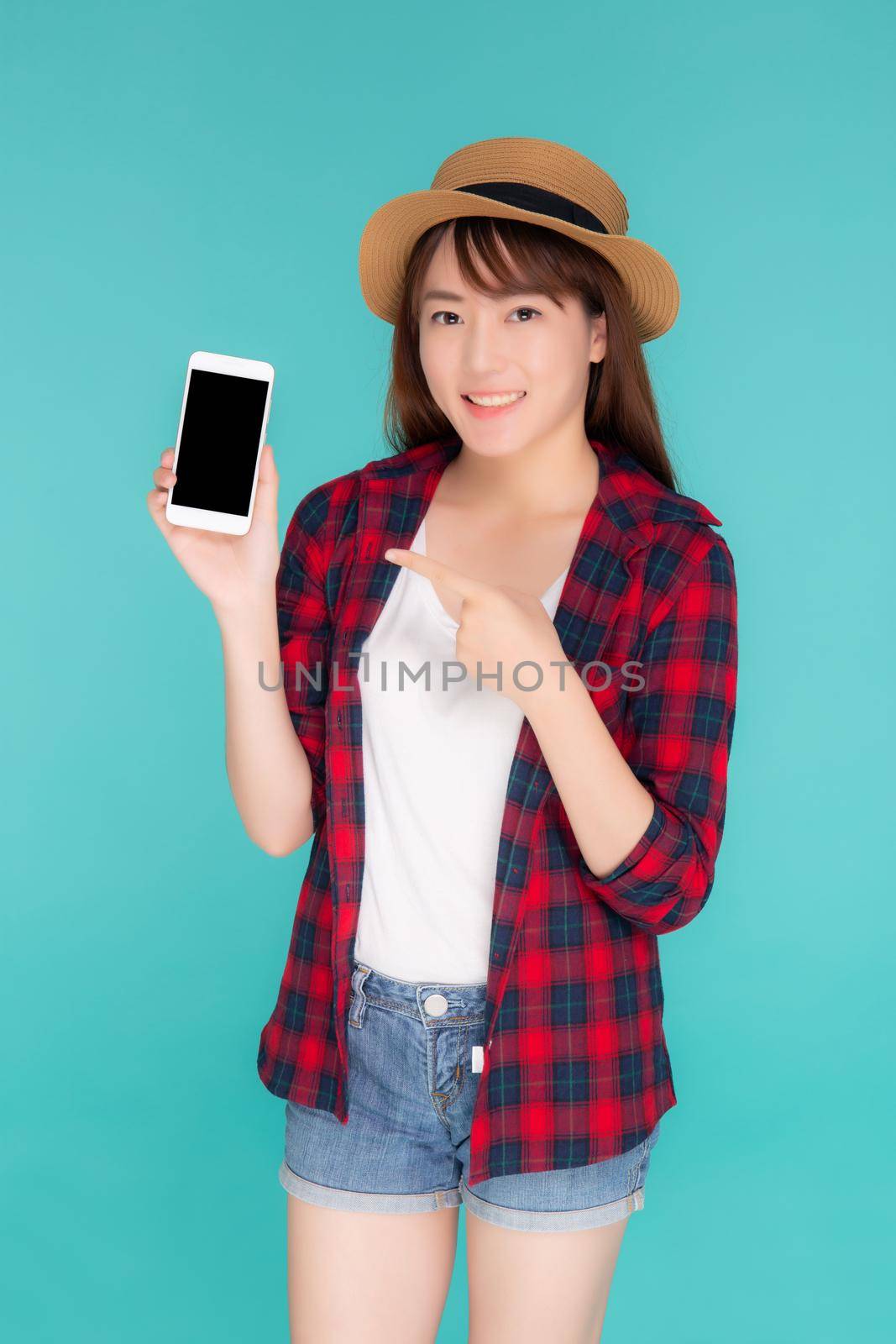 Beautiful young asian woman showing smart mobile phone for presenting and pointing something in travel summer trip in vacation isolated on blue background, asia girl holding smartphone.