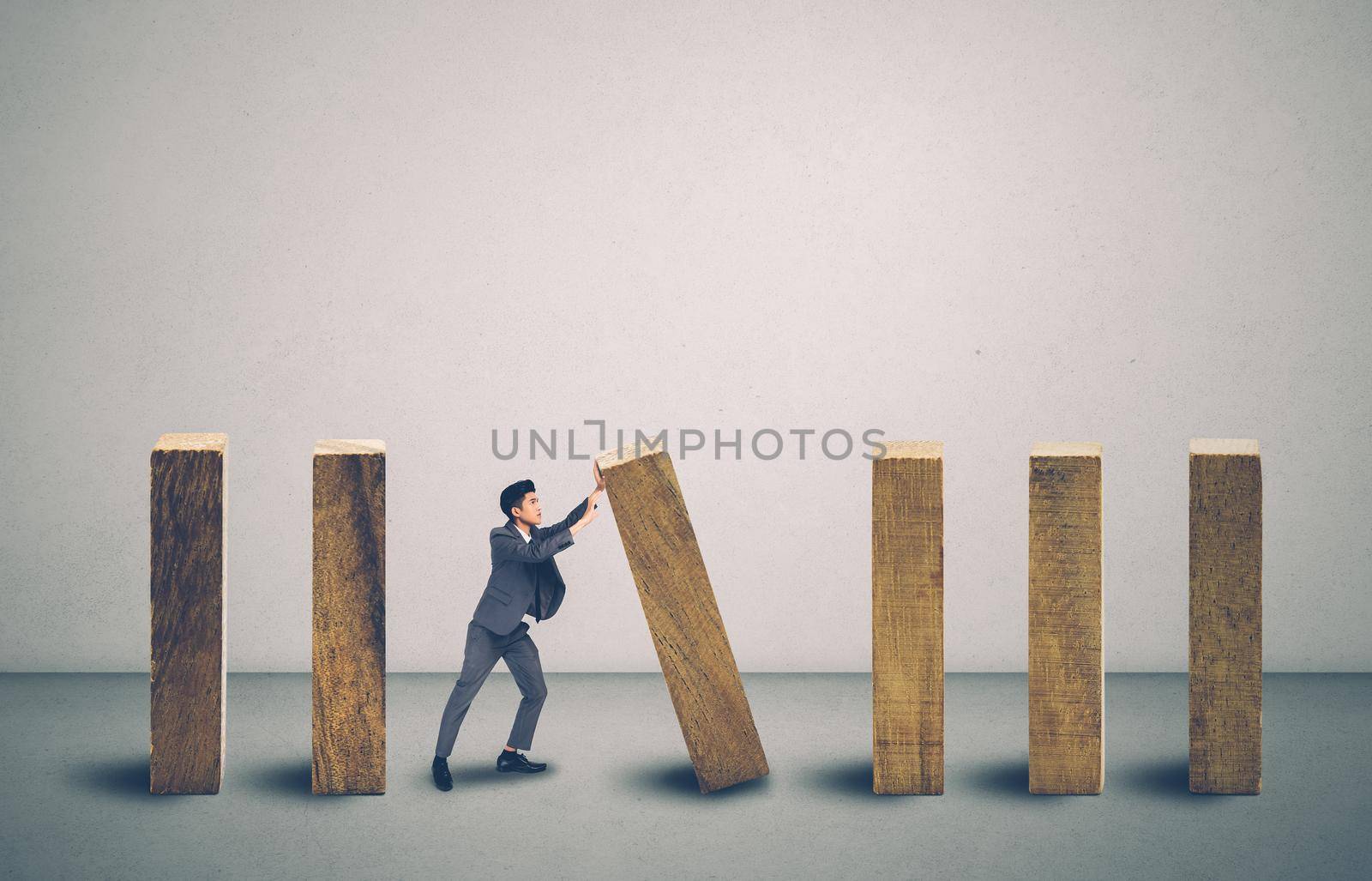 Risk of investment with economy, businessman push and stop wooden block domino with falling, management of strategy for prevention of bankruptcy, financial and insurance, crisis of business concept.