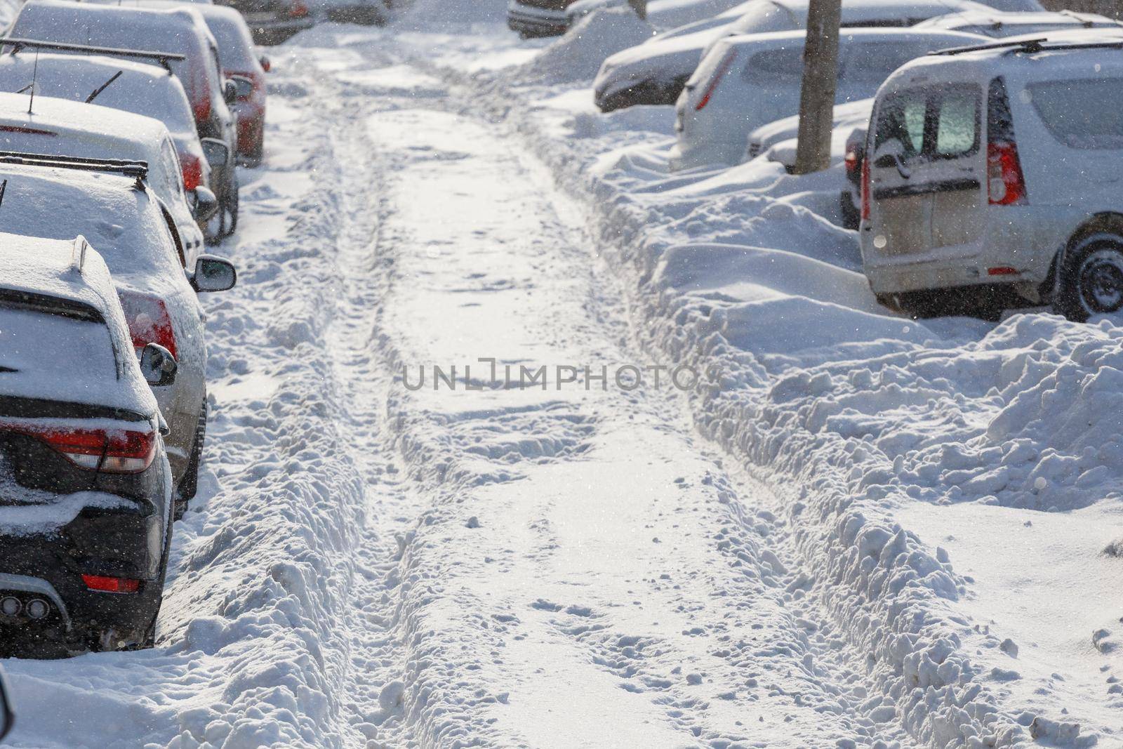 cars buried under snow in parking near residental building at sunny day light - close-up with selective focus
