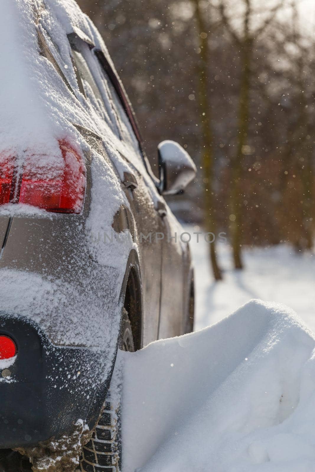 close-up view of car covered with snow and snow drift on its wheel, selective focus