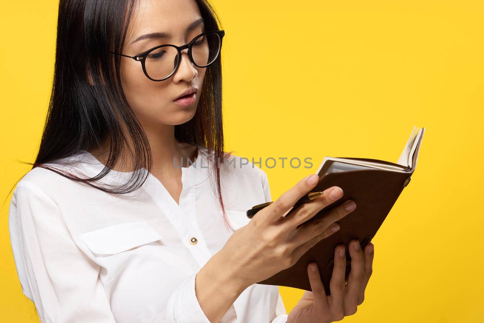 woman with a notebook in her hands in a white shirt official manager yellow background. High quality photo