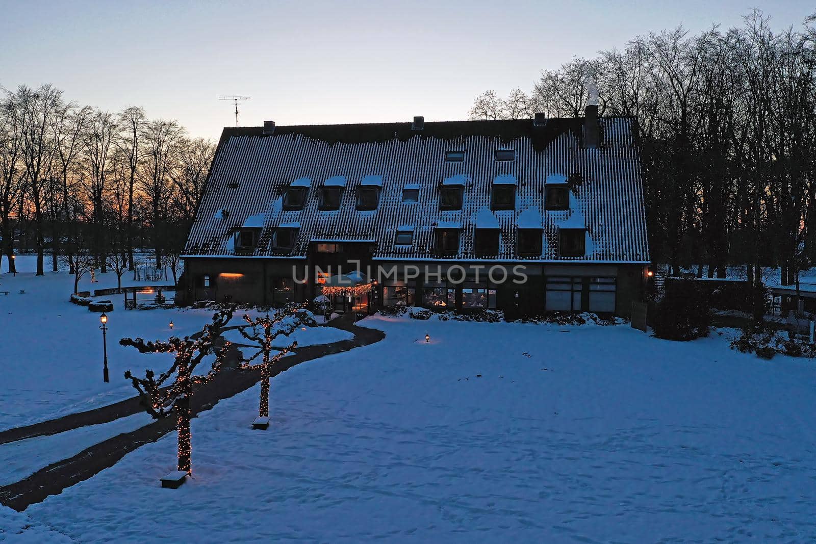 Traditional snowy farm house in winter in the countryside from the Netherlands at sunset