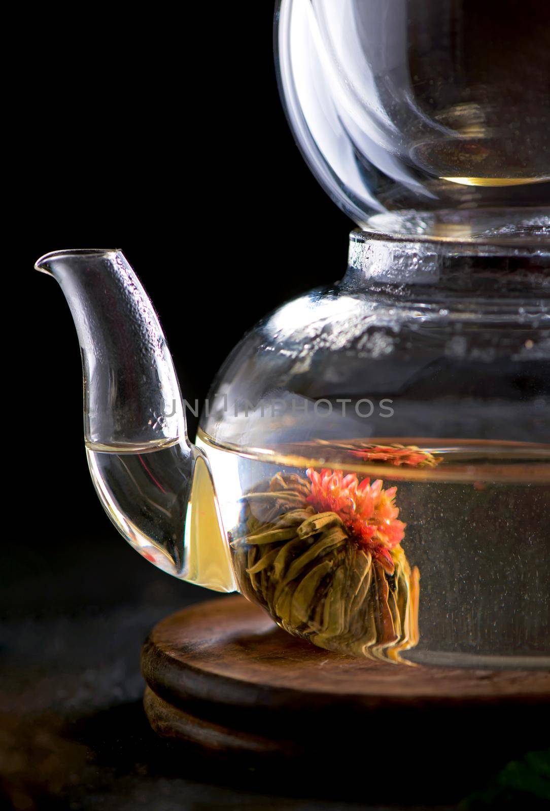 Teapot with tea surrounded with green leaves, tea ceremony, green tea in a transparent cup