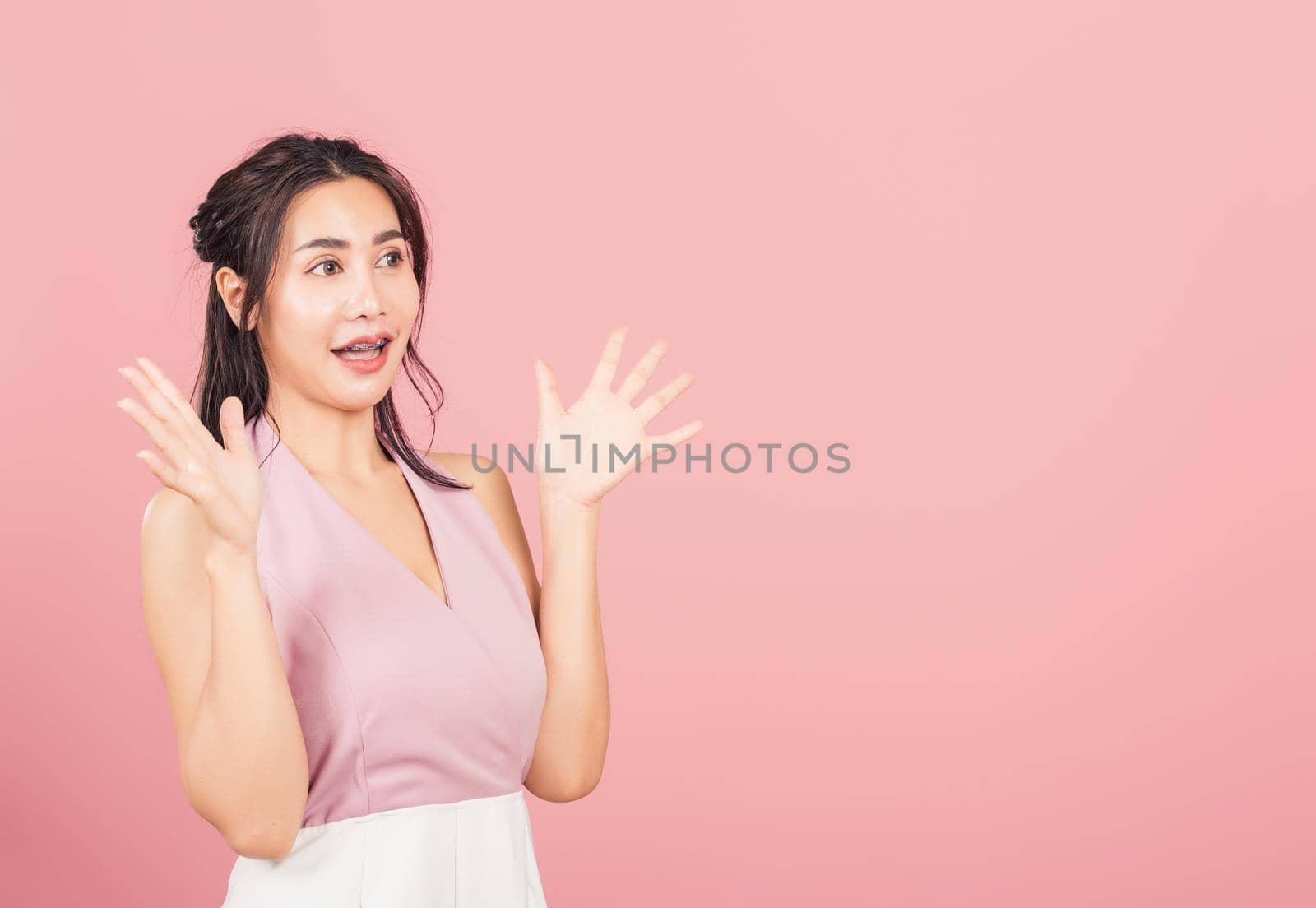 Happy Asian portrait beautiful cute young woman standing winning and surprised excited screaming open mouth raise hands, studio shot isolated pink background, Thai female wow with copy space