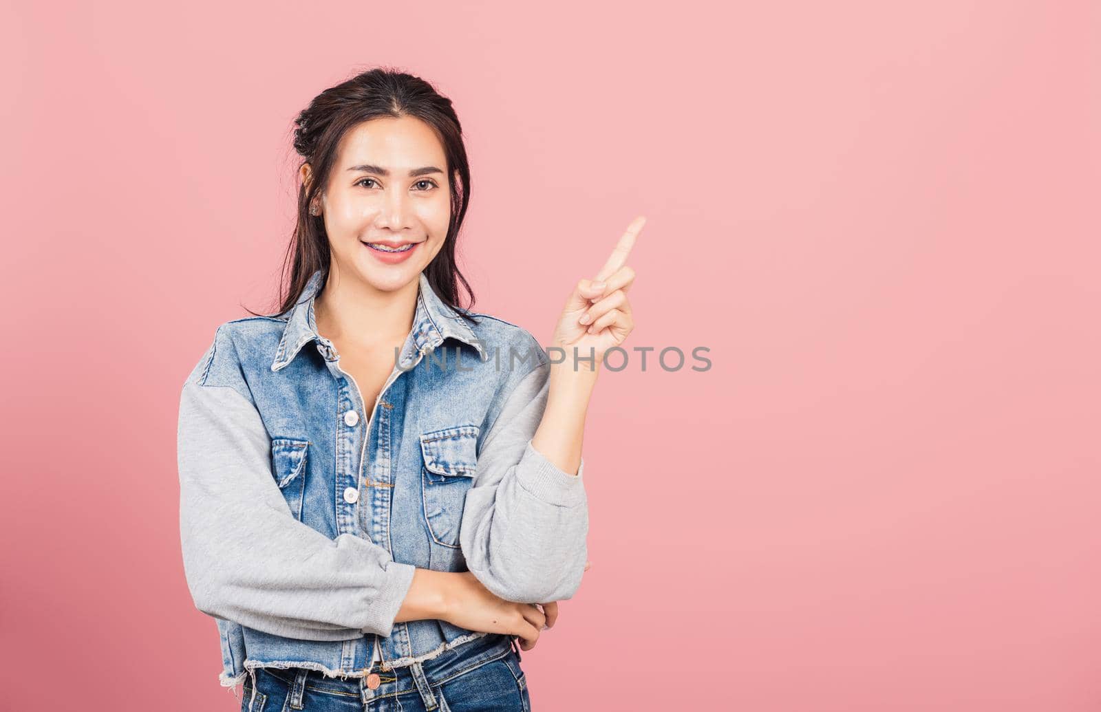 woman standing smiling indicate finger empty space by Sorapop