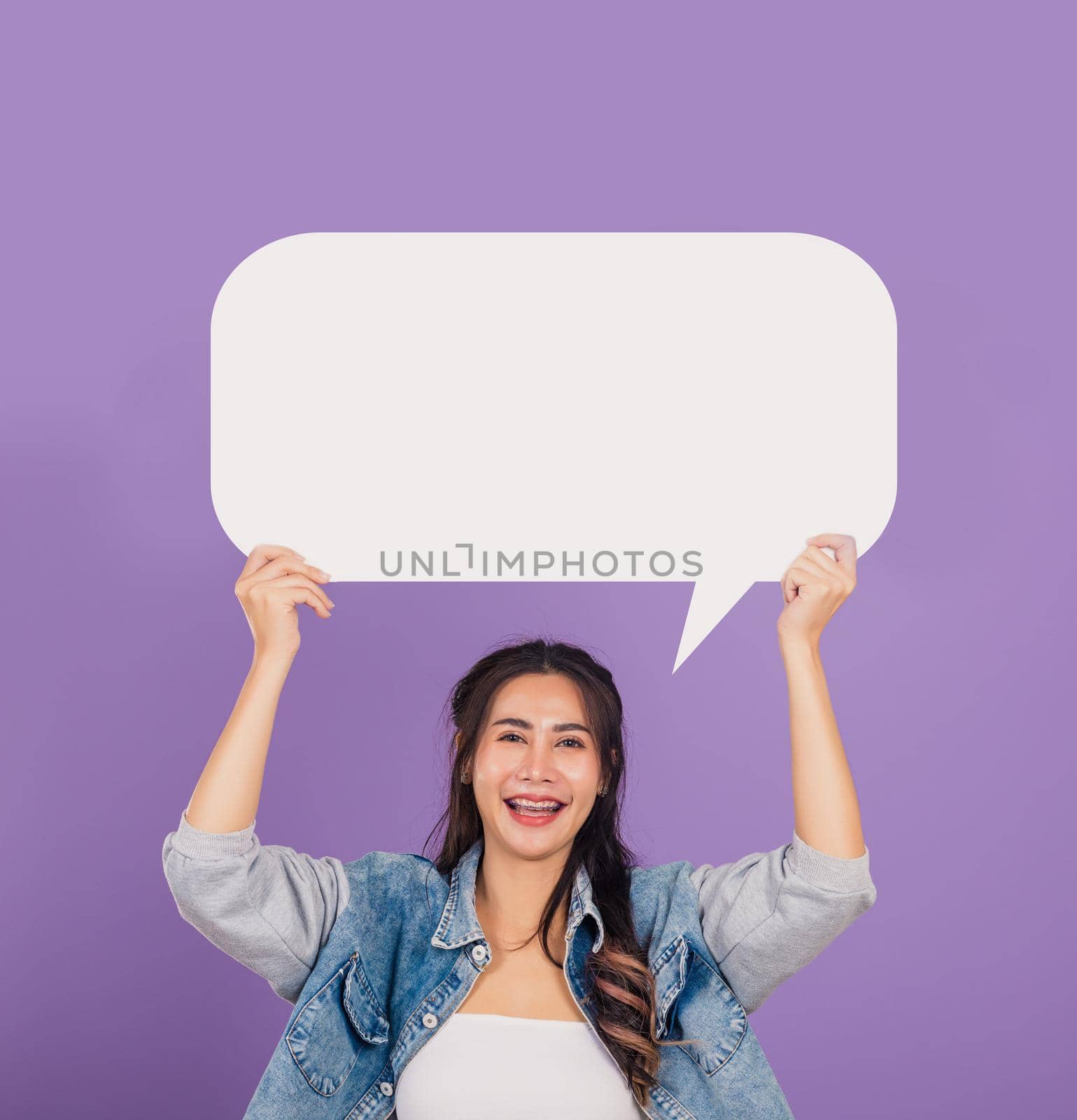woman smiling excited wear denims hold empty speech bubble sign by Sorapop