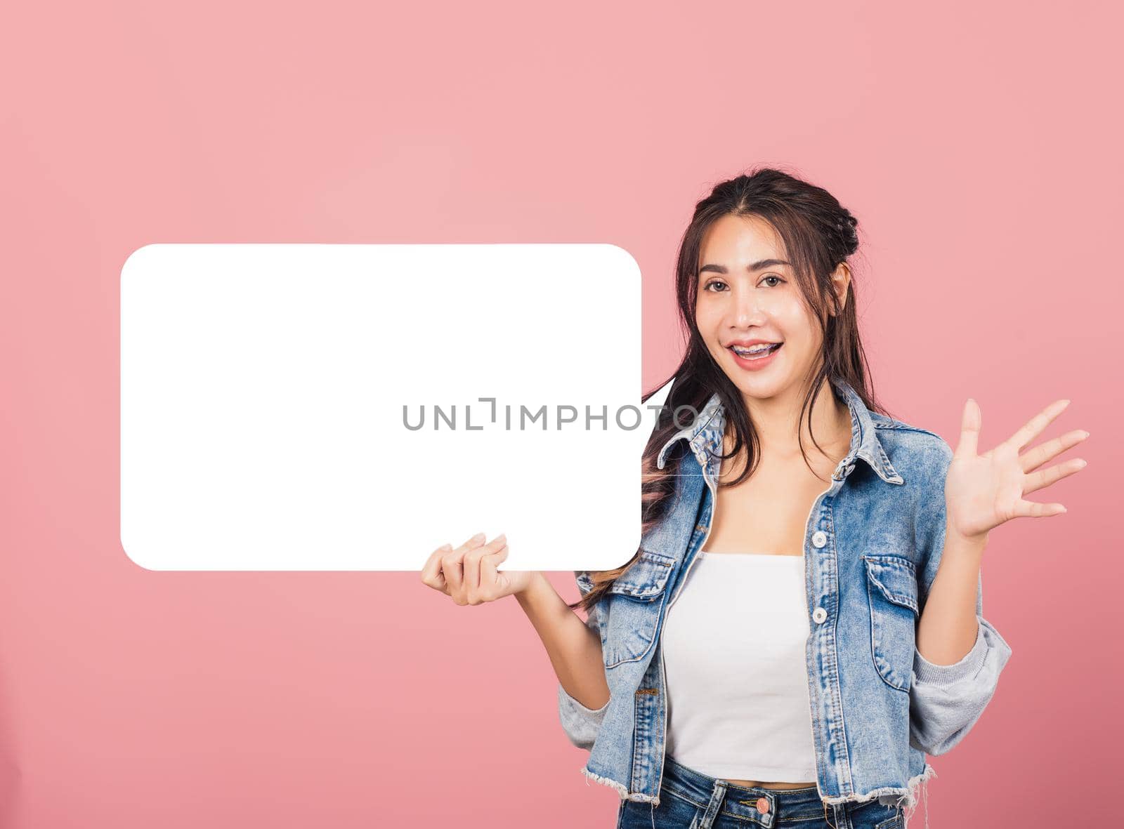 woman smiling excited wear denims holding empty speech bubble sign by Sorapop