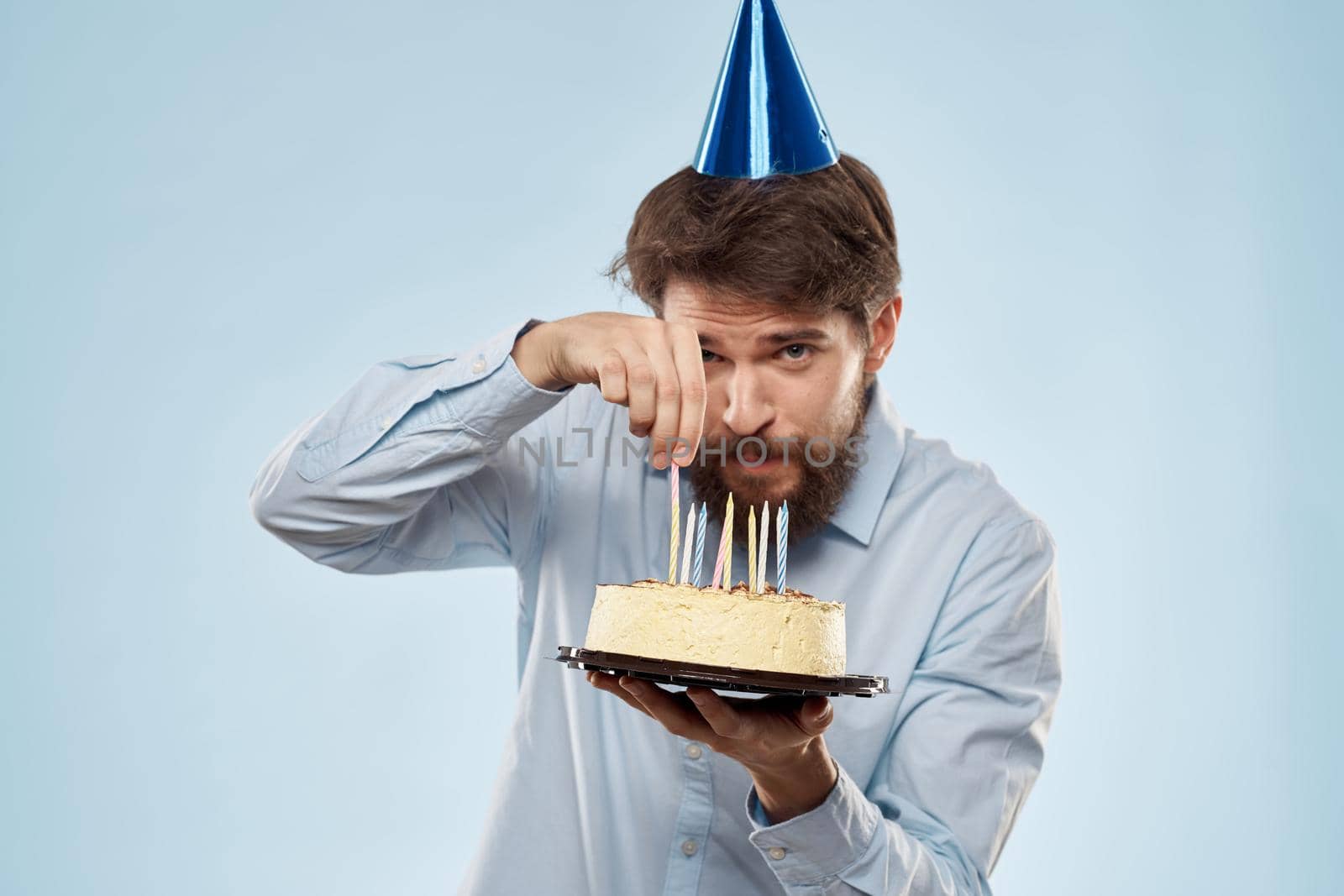 cake in a plate and birthday man with a cap on his head blue backgroun. High quality photo