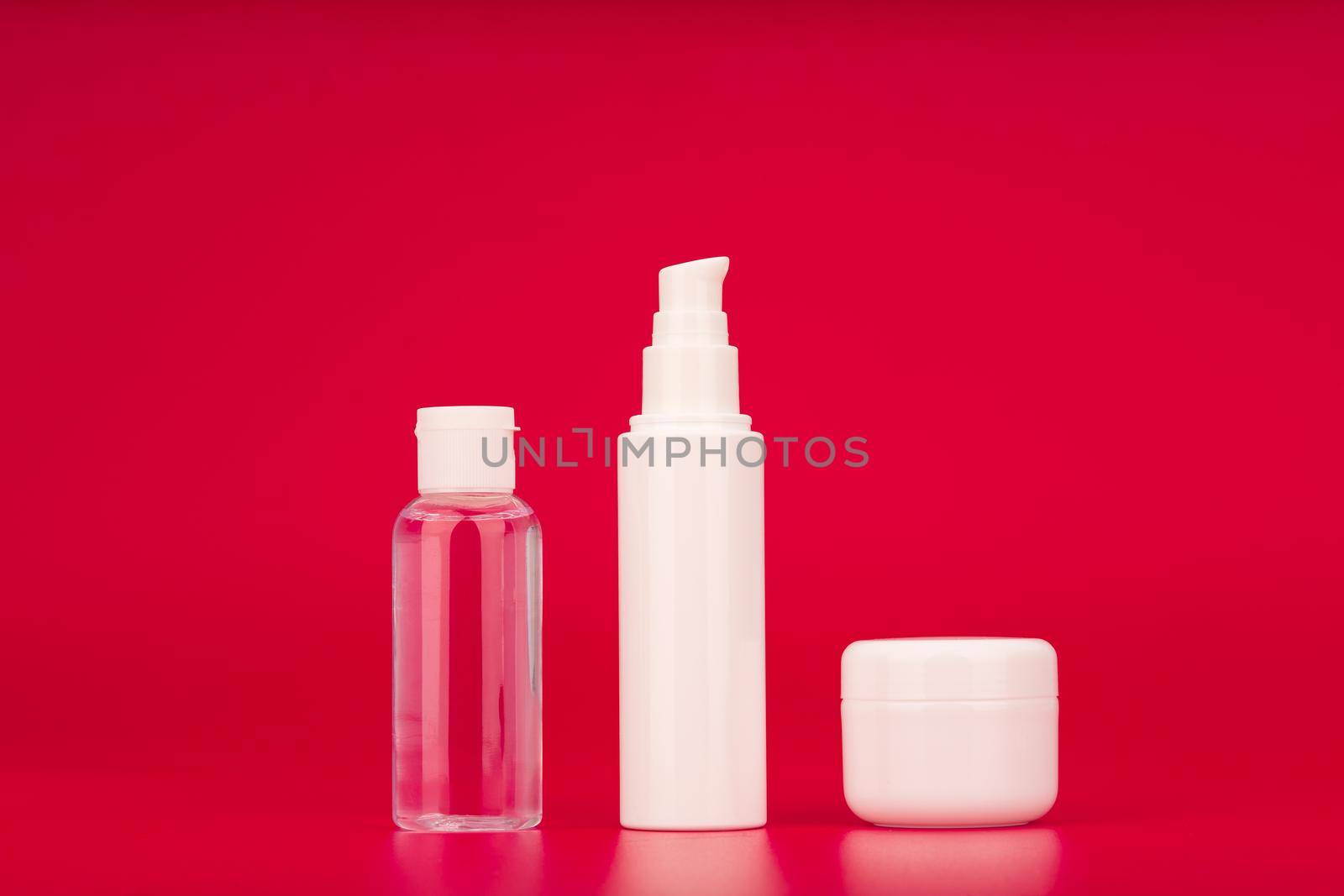 Skin care products against red background. Lotion, face cream and under eye cream set. Concept of beauty cosmetics for daily use