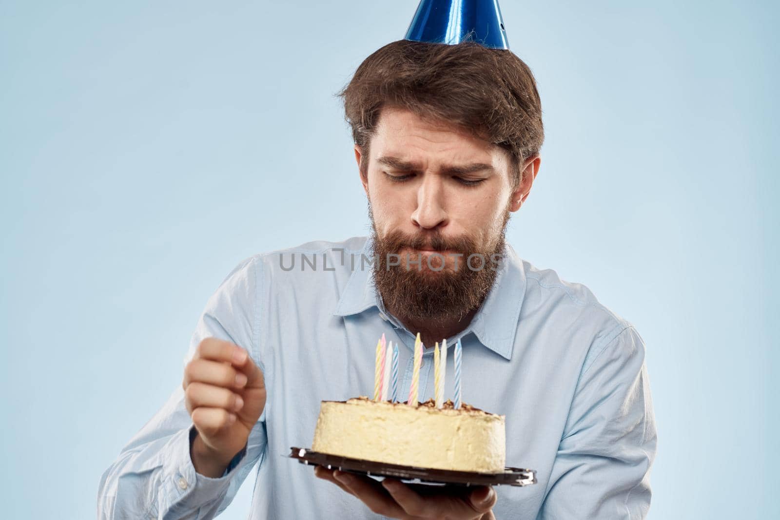 cake in a plate and birthday man with a cap on his head blue backgroun. High quality photo