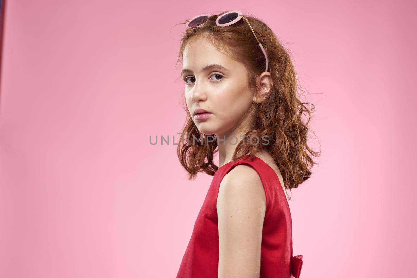 Cheerful little girl childhood dark glasses red dress lifestyle pink background by SHOTPRIME