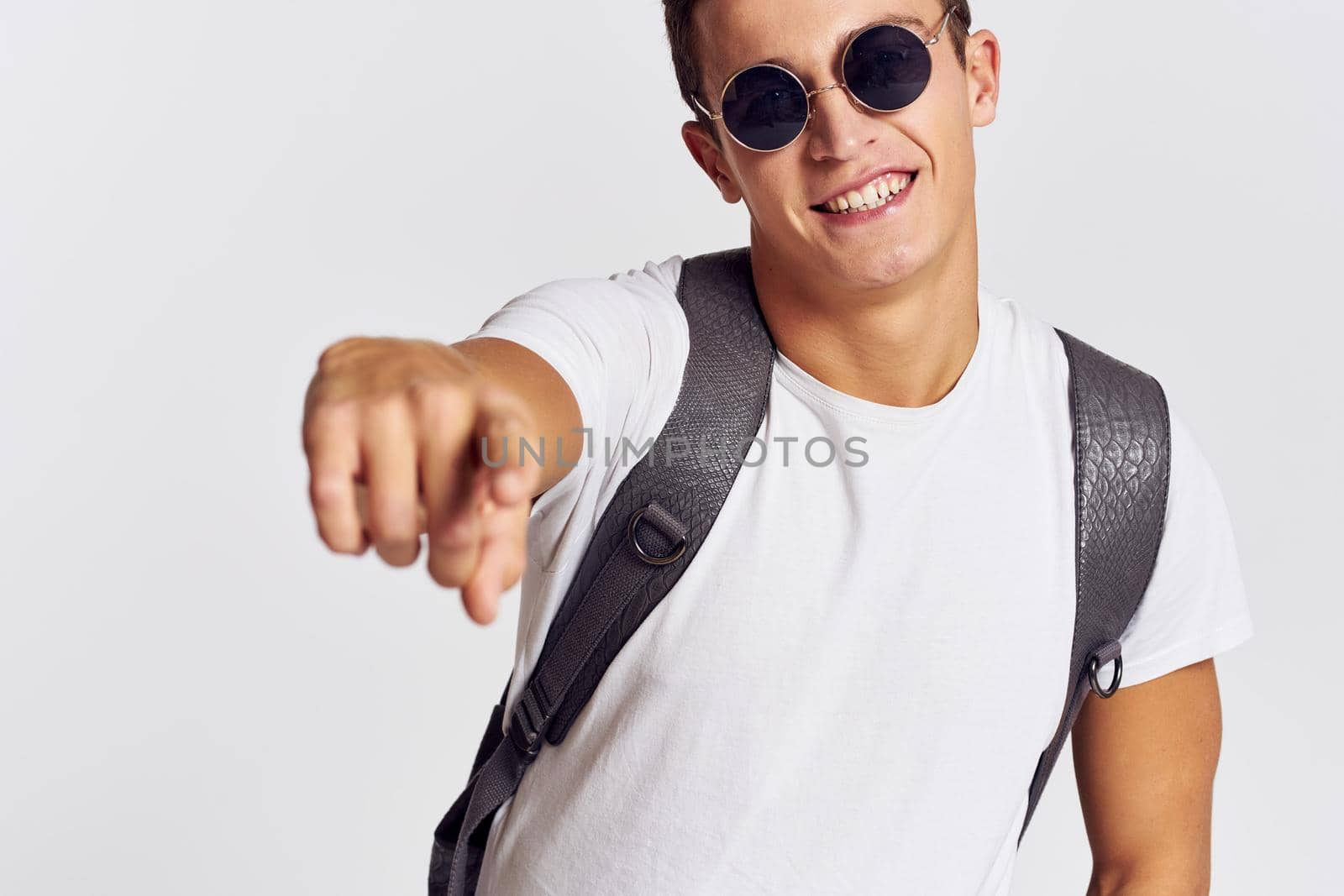 handsome man with backpack on his back gesturing with his hands in a t-shirt and wearing glasses Copy Space portrait cropped view