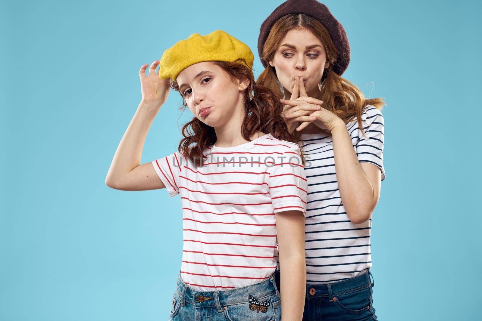Fashion sisters in hats fun lifestyle blue background studio. High quality photo